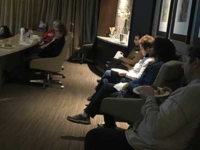 people listening to speakers at potluck dinner event