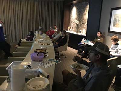 people at potluck dinner event listening to speakers