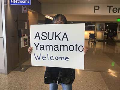 Kumiko holding welcome sign at airport
