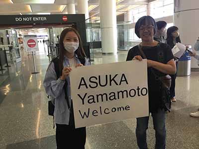 Kumiko (host mother) and student holding sign at airport