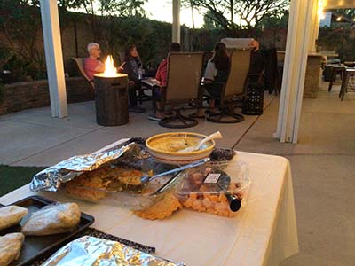 people sitting by fire at potluck dinner in back yard