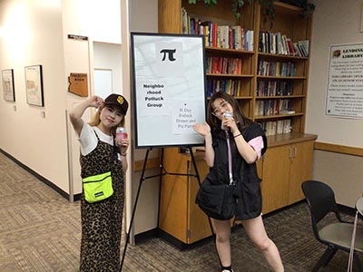 two Japanese ESL students in front of whiteboard naming event, on easel