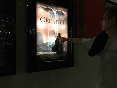 Lance pointing to backlit movie poster for The Creator