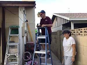 neighbors gather to scrape and paint trim on home of elderly neighbor Nellice Reidhead